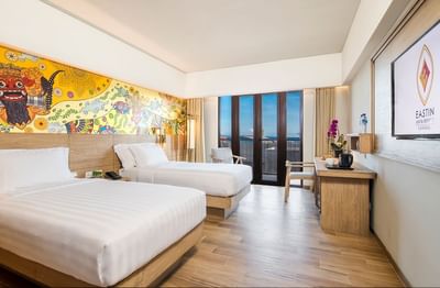 Elegant wallpaper and two cozy beds in Superior Room at Eastin Ashta Resort Canggu