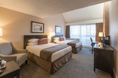 Traditional Room With two Queen sized beds, an armchair and a TV at Embassy Inn Victoria