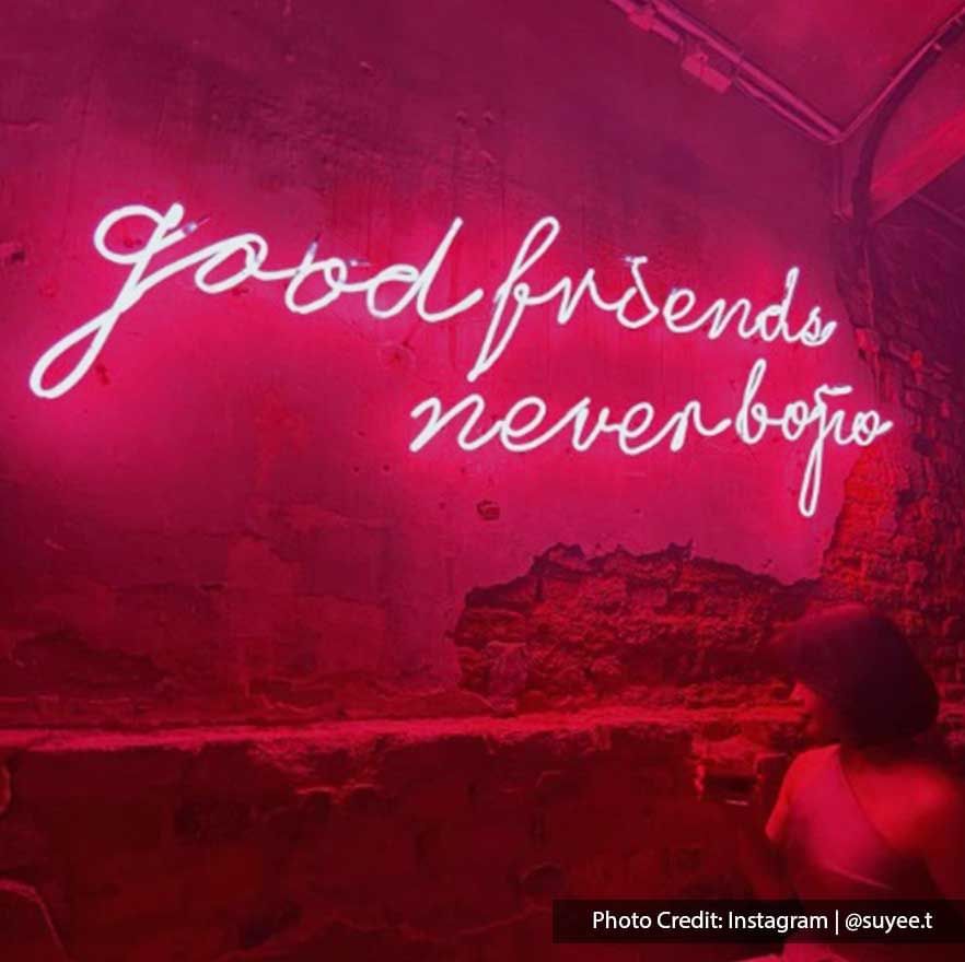 A lady was taking pictures with the neon sign on the wall at Good Friends Club - Lexis Suites Penang