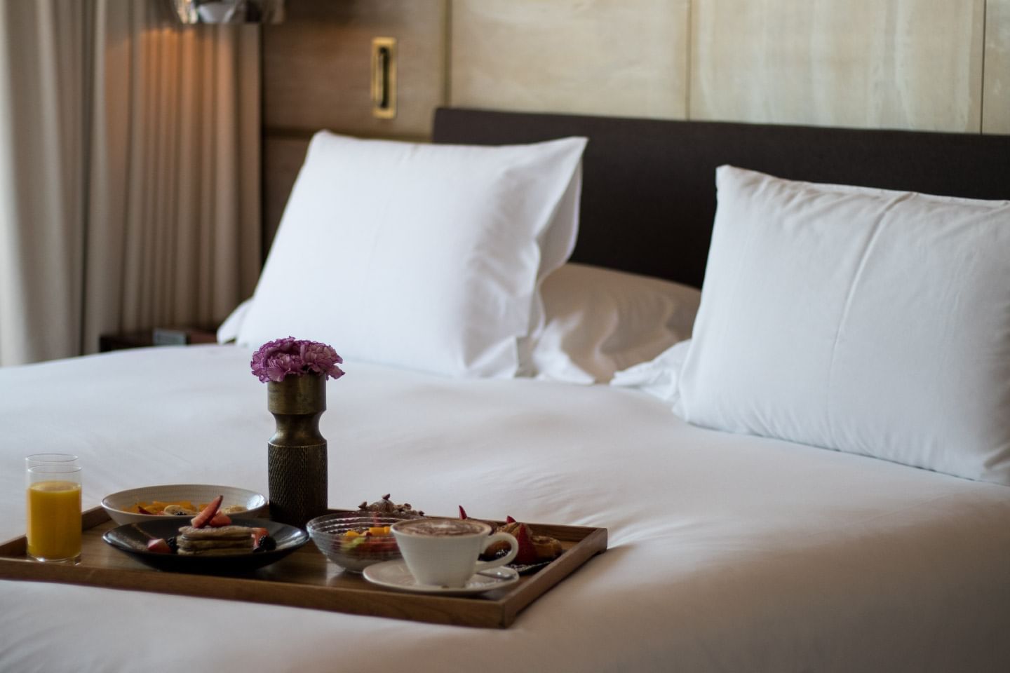 Beautifully arranged breakfast tray on a plush bed with a flower vase at Almanac Barcelona