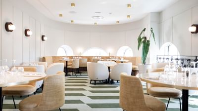 A dining room with white chairs, striped green and white floors, and a white-walled curved interior.
