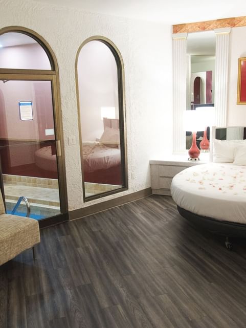 Interior of Garden of Eden Apple with a bed arranged with flower petals & a pool view at Cove Pocono Resorts