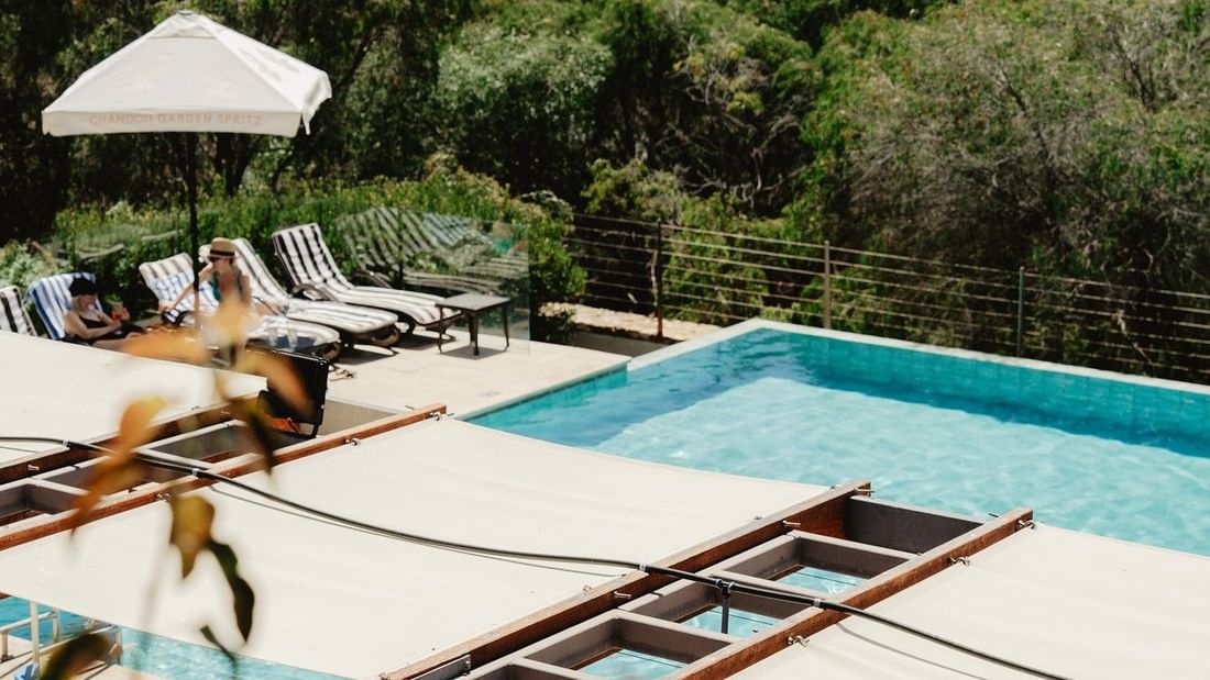 Outdoor pool with white lounge chairs overlooking lush greenery and ocean views for Pair'd Margaret River Region 2026