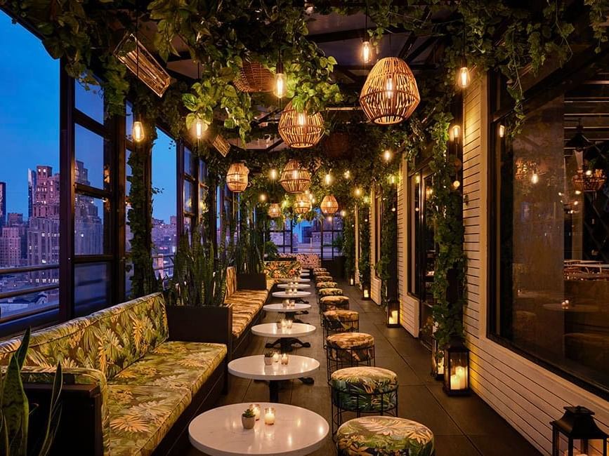 Rooftop terrace at dusk with lounge seating, chairs and lights