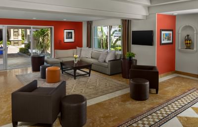 Lobby with armchairs by a sofa under bright recessed lighting at Anaheim Portofino Inn & Suites