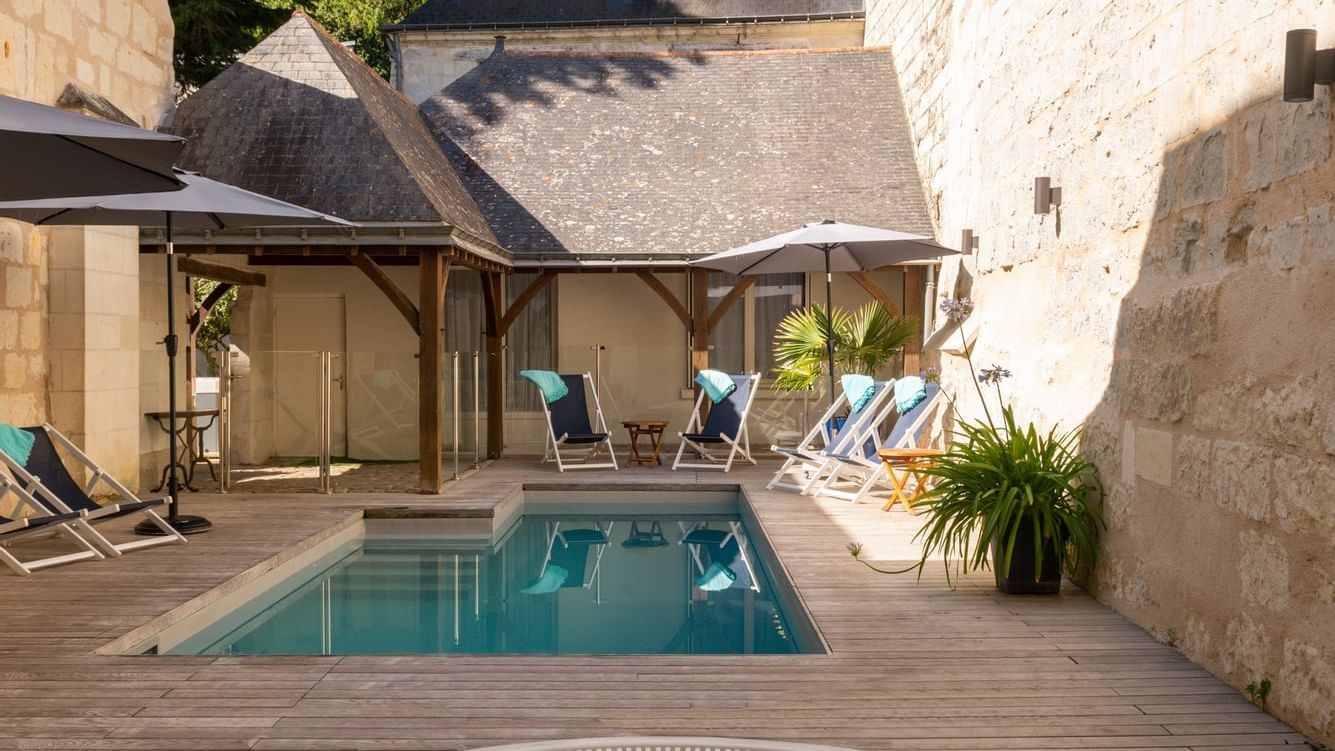 A plunge pool with a pool chairs by it in Originals Hotels