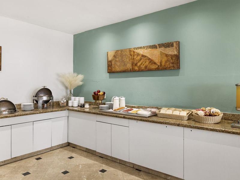 Esquina del buffet del comedor en Fiesta Inn Express Nuevo Laredo con fruta, pasteles y platos calientes