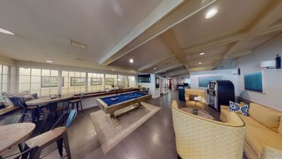 Game lounge with a blue billiard table on a rug beside yellow patterned armchairs inside the Avon Old Farms Hotel