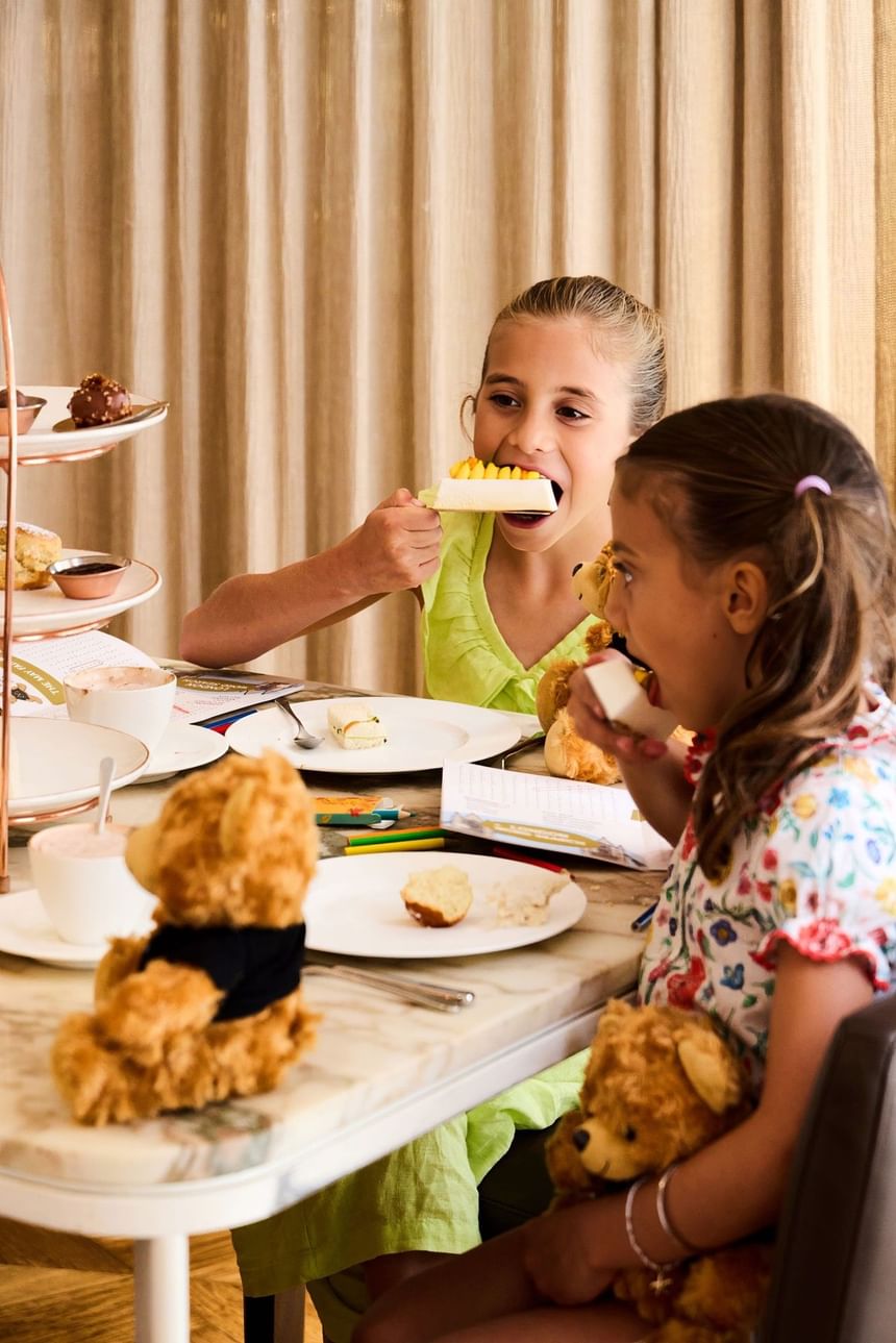 Two young girls enjoying Children's afternoon tea with scones and cakes at May Fair Kitchen, Mayfair