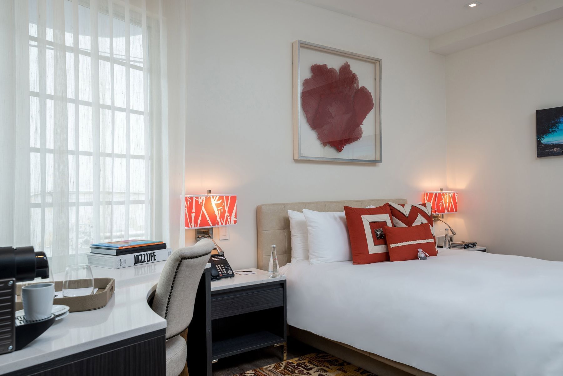A hotel room with a king-sized bed, desk, and window