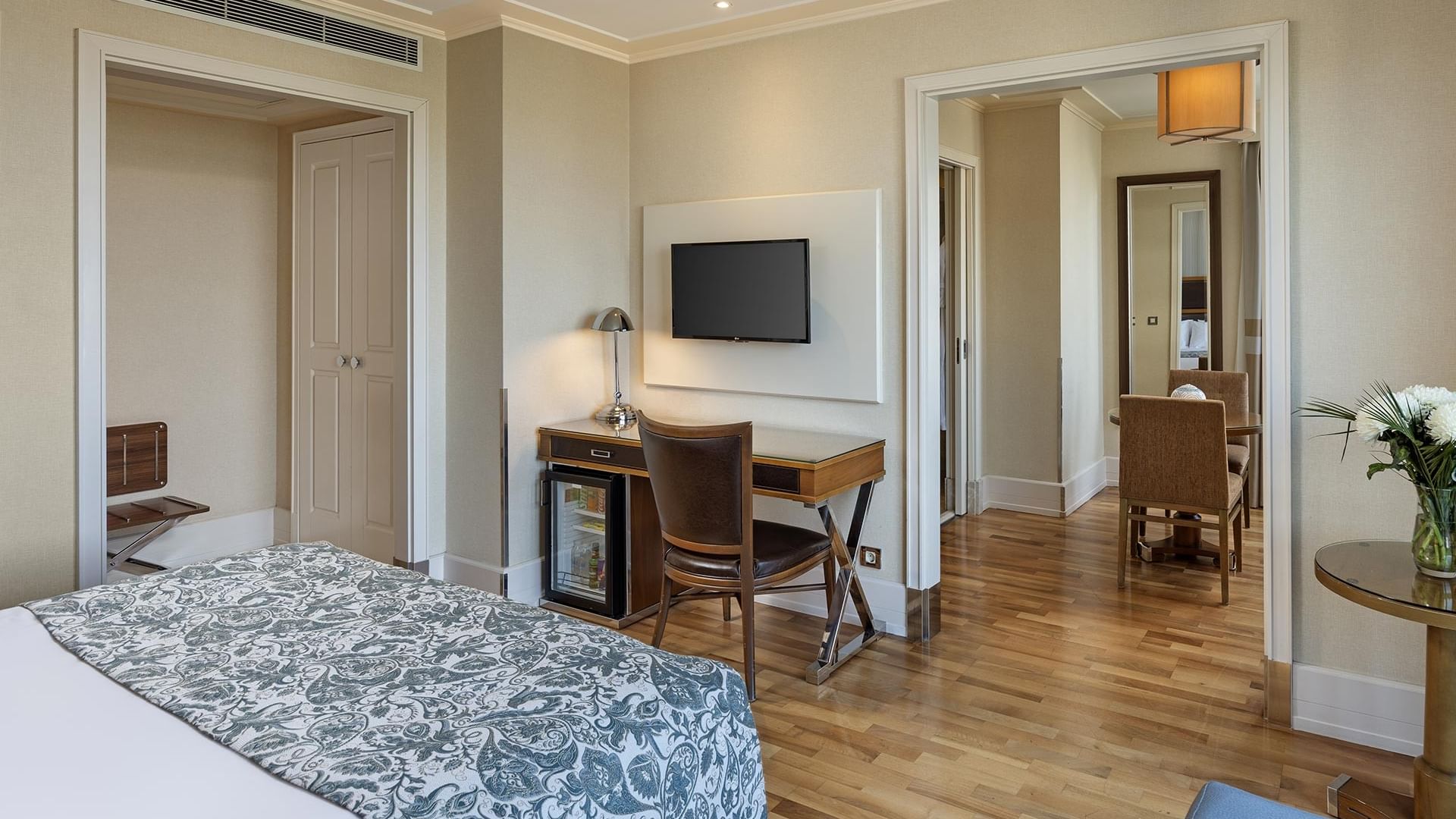 Titanic City Taksim'deki deluxe odada, yatak, çalışma masası, sandalye, televizyon, masa ve sandalyeler.