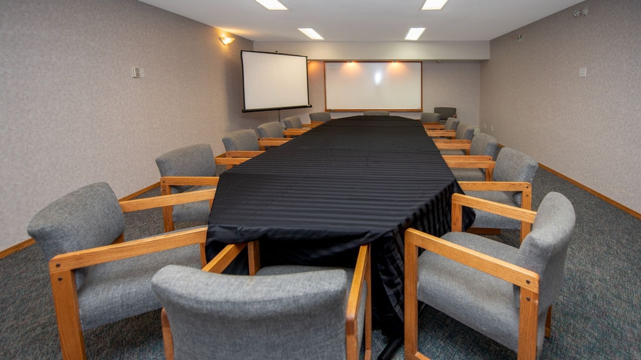 A meeting room with a table, gray chairs, and a whiteboard.