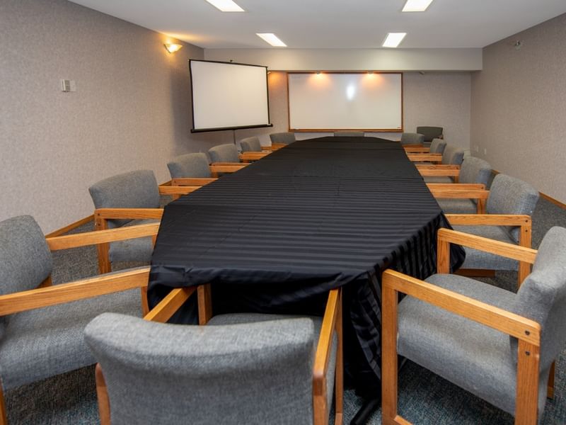 A meeting room with a table, gray chairs, and a whiteboard.