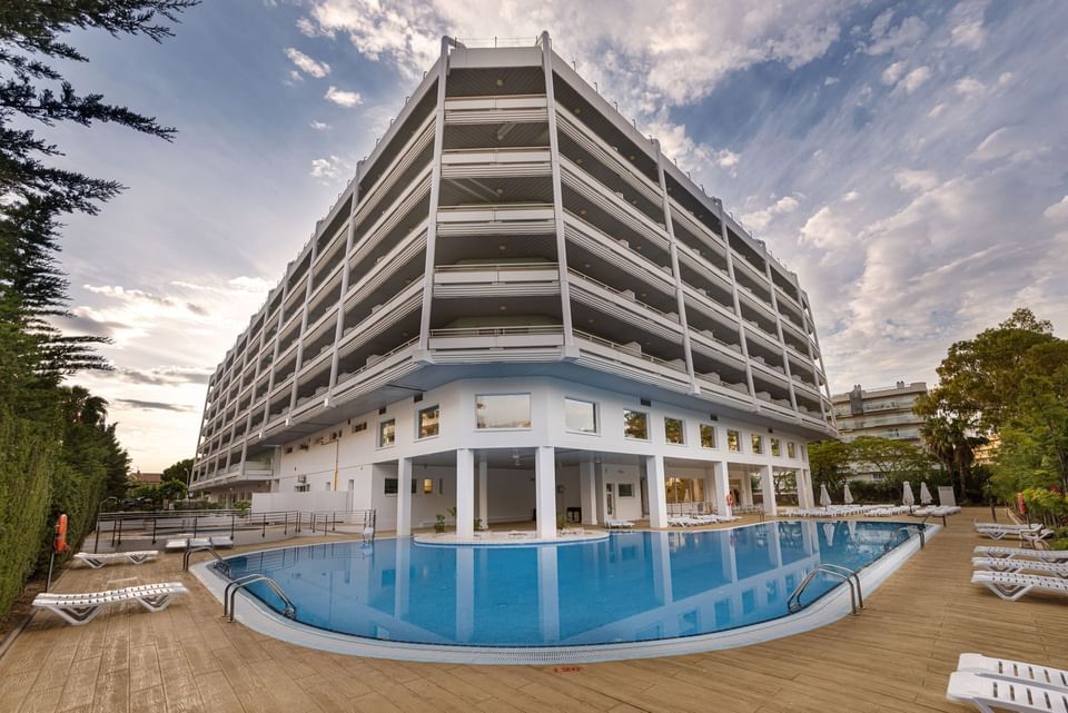 The exterior of Hotel Piramide Salou with an outdoor swimming pool & sun loungers