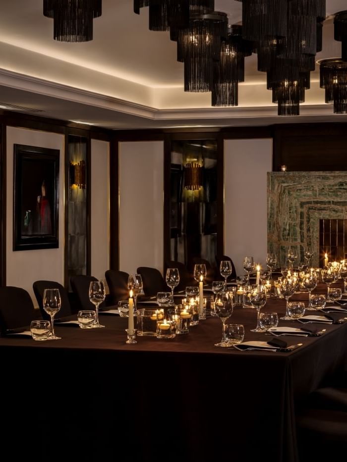 Elegantly set dining table with candles and wine glasses in a sophisticated room at The May Fair Hotel, London.
