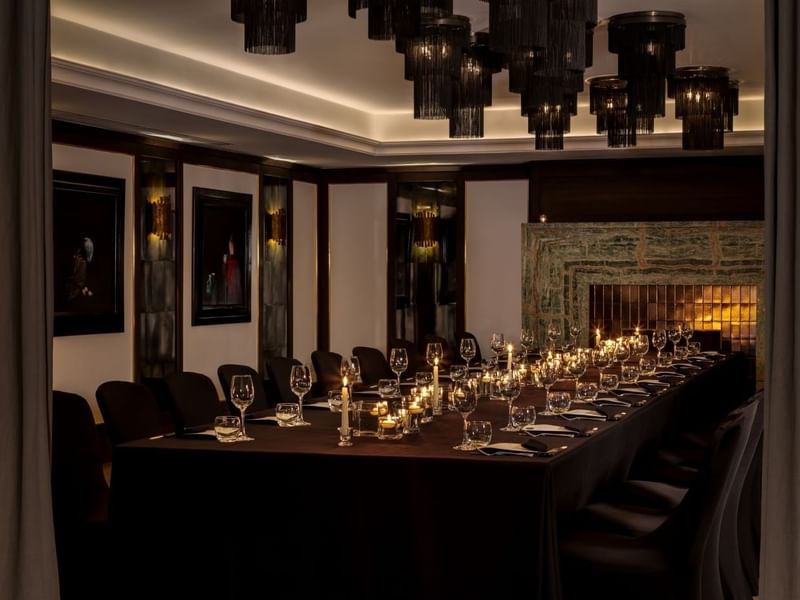 Elegantly set dining table with candles and wine glasses in a sophisticated room at The May Fair Hotel, London.