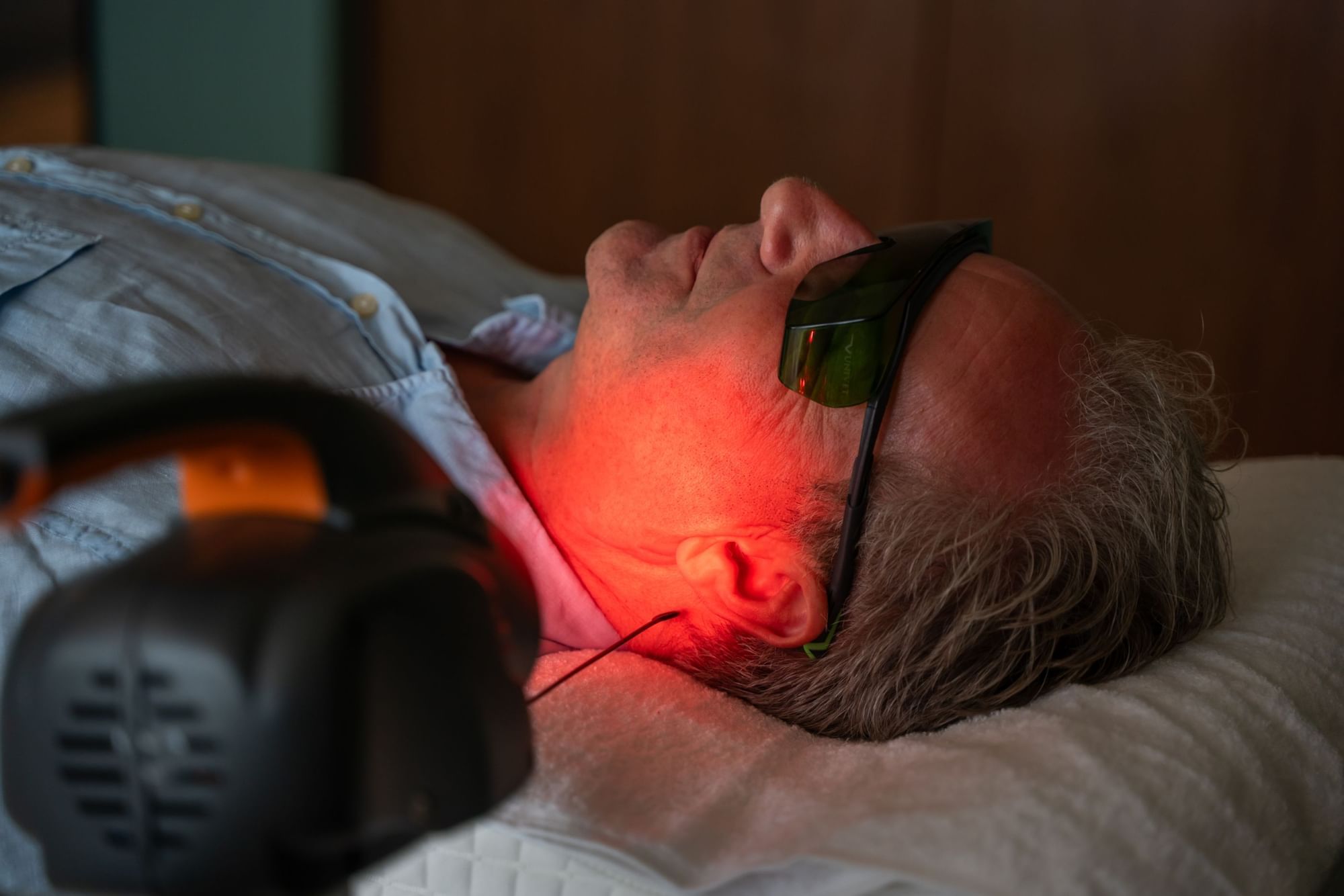 Persoon op behandelbed draagt een veiligheidsbril tijdens lasertherapie bij Tinnitus Relief Therapy, Golden Rock Resort