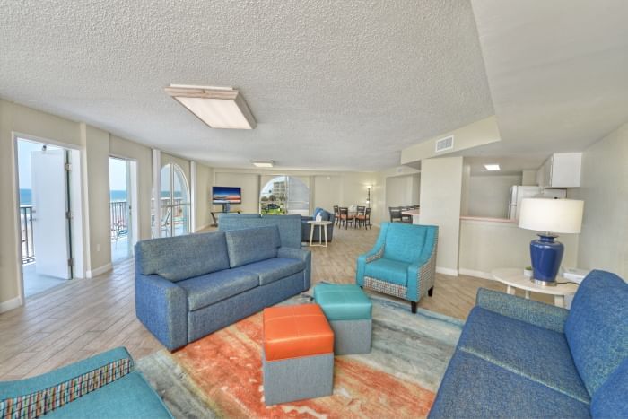 A wide view of a living room with a sofa, armchair, and balcony with ocean view.