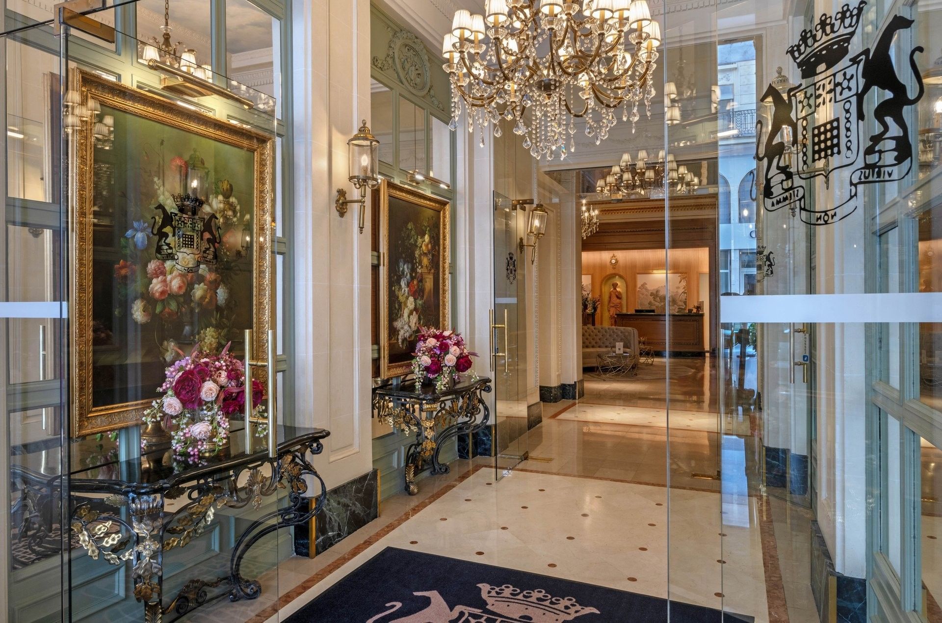Hotel Westminster Paris entrance featuring floral arrangements by ornate black tables, under a crystal chandelier