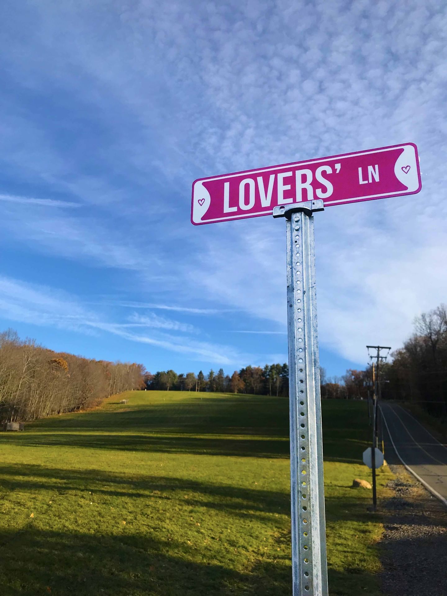 Lovers' Lane signboard with a backdrop of a green field and clear blue sky near Cove Pocono Resorts