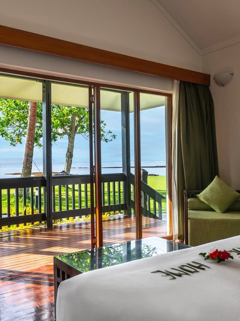 Green armchair by large glass doors under high ceilings near a patio in Studio Villa at The Naviti Resort - Fiji