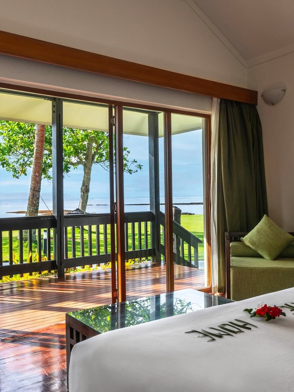 Green armchair by large glass doors under high ceilings near a patio in Studio Villa at The Naviti Resort - Fiji