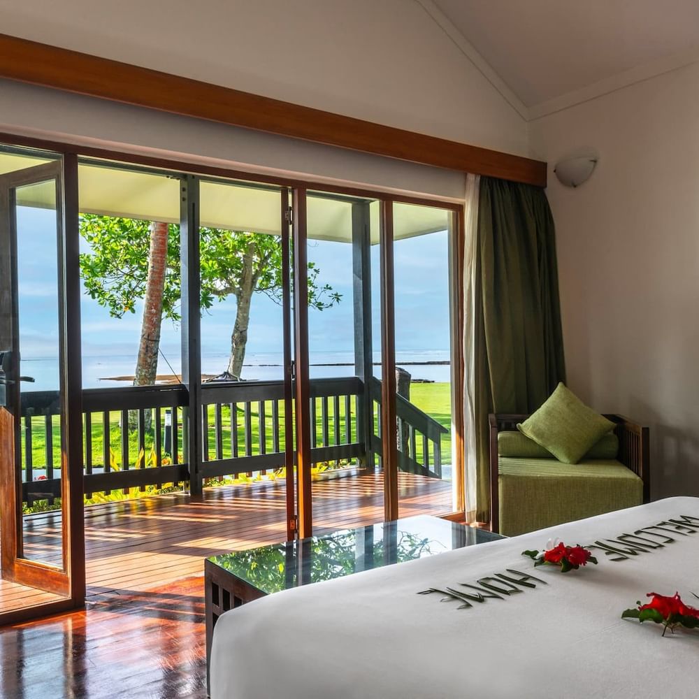 Green armchair by large glass doors under high ceilings near a patio in Studio Villa at The Naviti Resort - Fiji