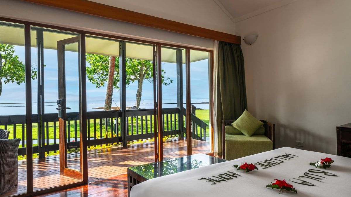 Green armchair by large glass doors under high ceilings near a patio in Studio Villa at The Naviti Resort - Fiji