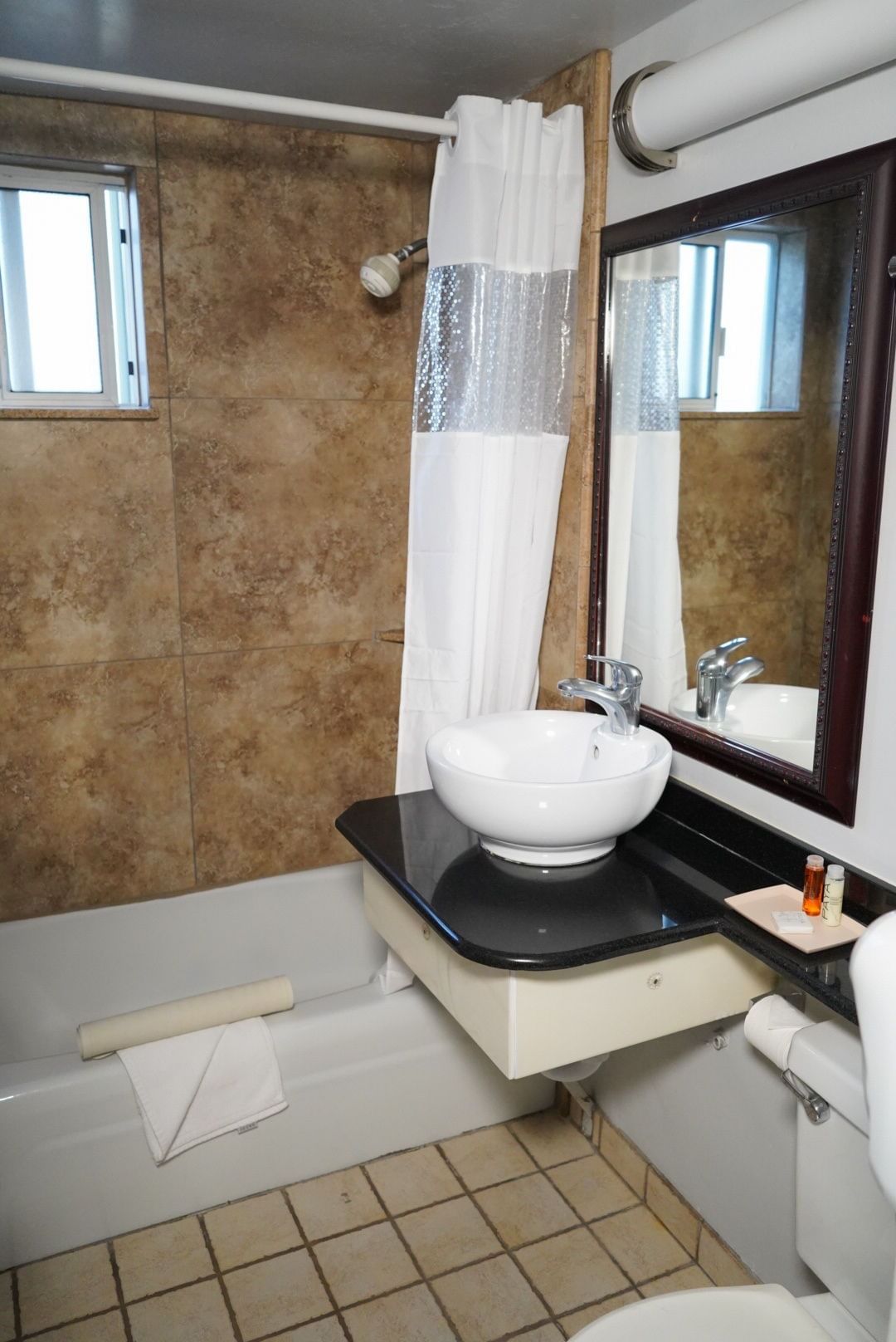 A bathroom with a white sink, black countertop, and a bathtub with a shower curtain.