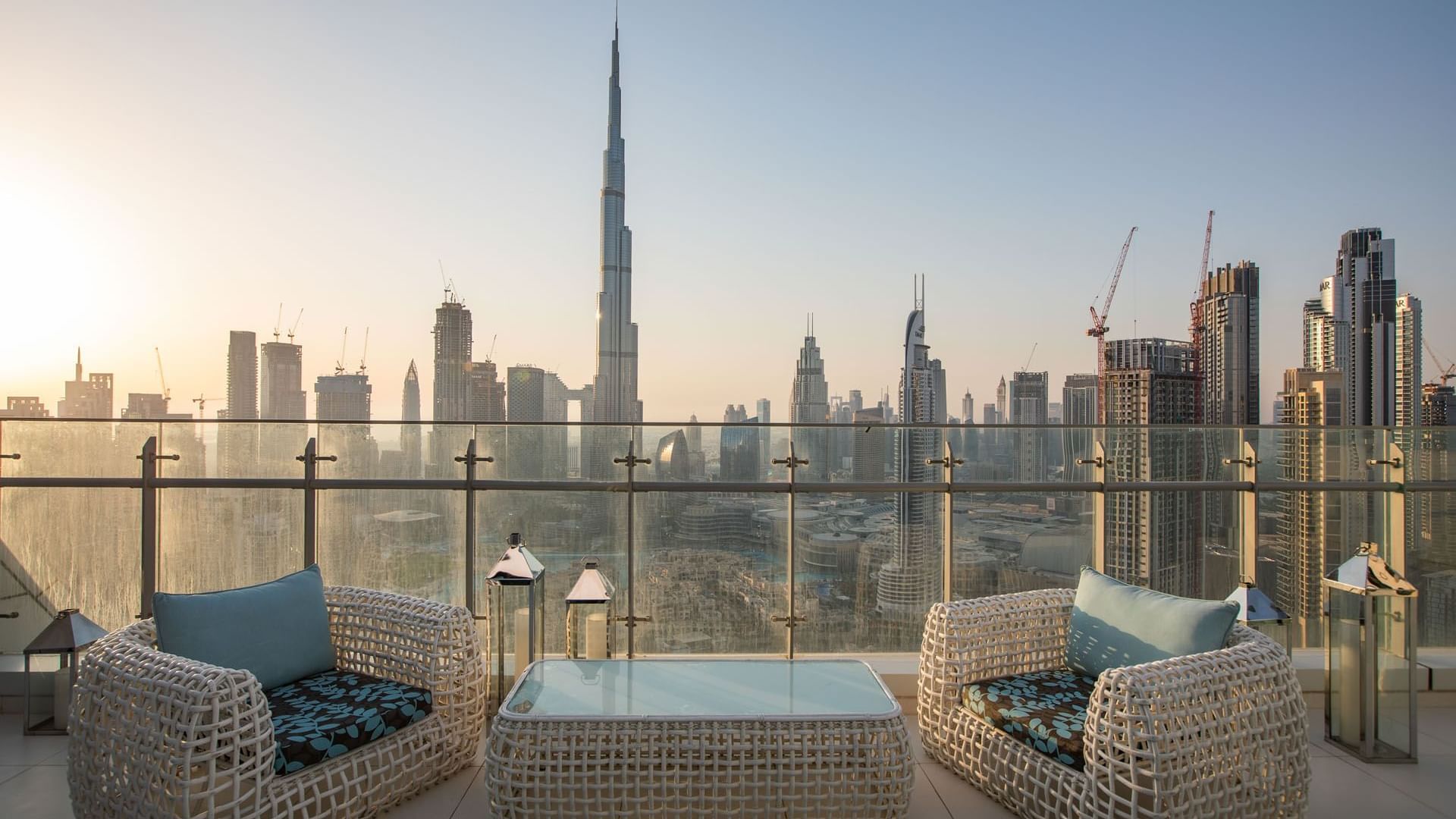A balcony with wicker chairs overlooking the Burj Khalifa at DAMAC Maison Distinction