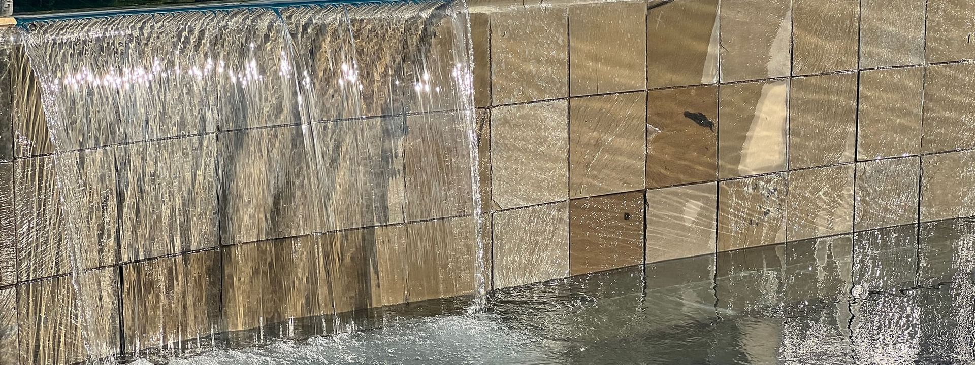 Water flowing into a pool with lounge chairs at Warwick Le Lagon in Efate