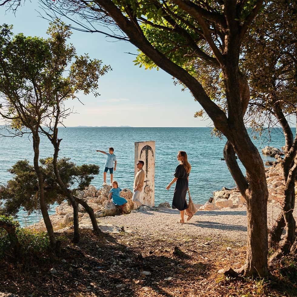 Family enjoying a scenic seaside view under trees in an advertisement for Winter Escape offer.