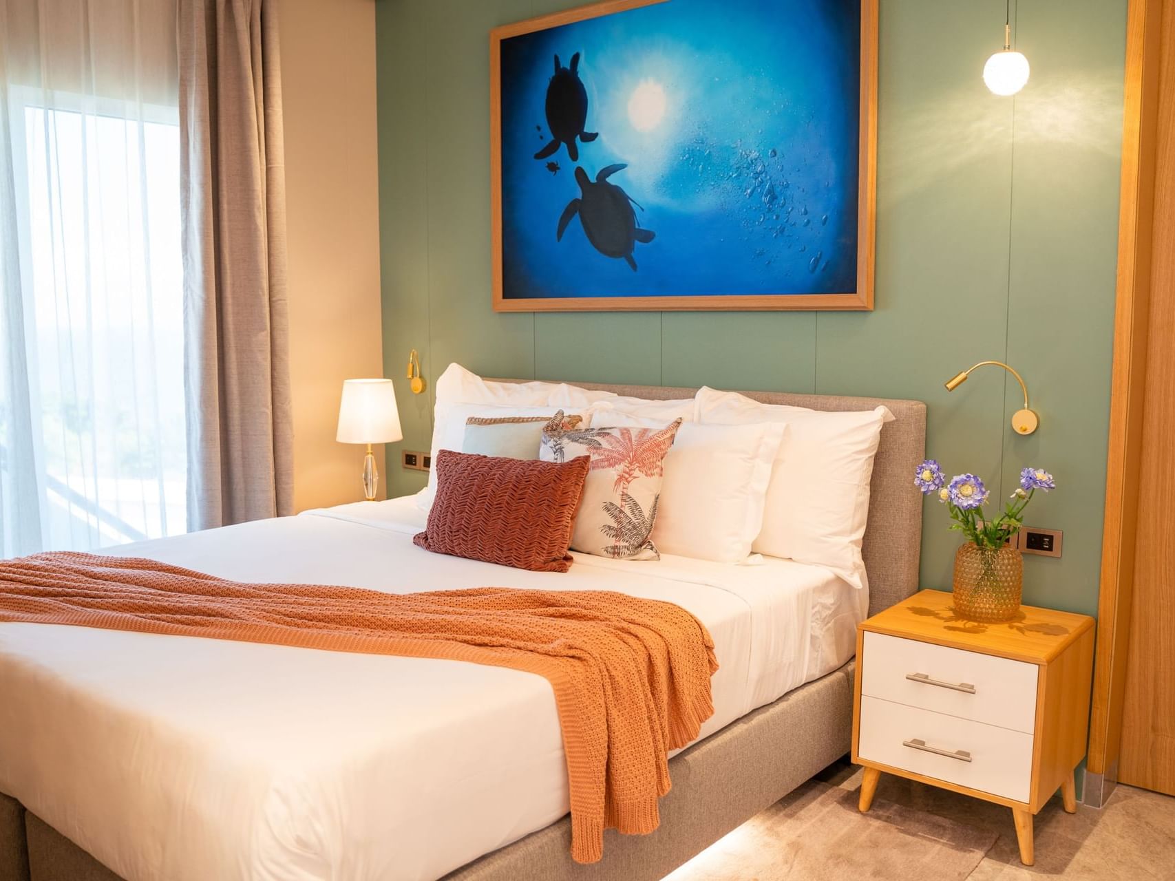 Villa Suite featuring a comfy bed, nightstands, and a turtle-themed painting on turquoise walls at Golden Rock Resort
