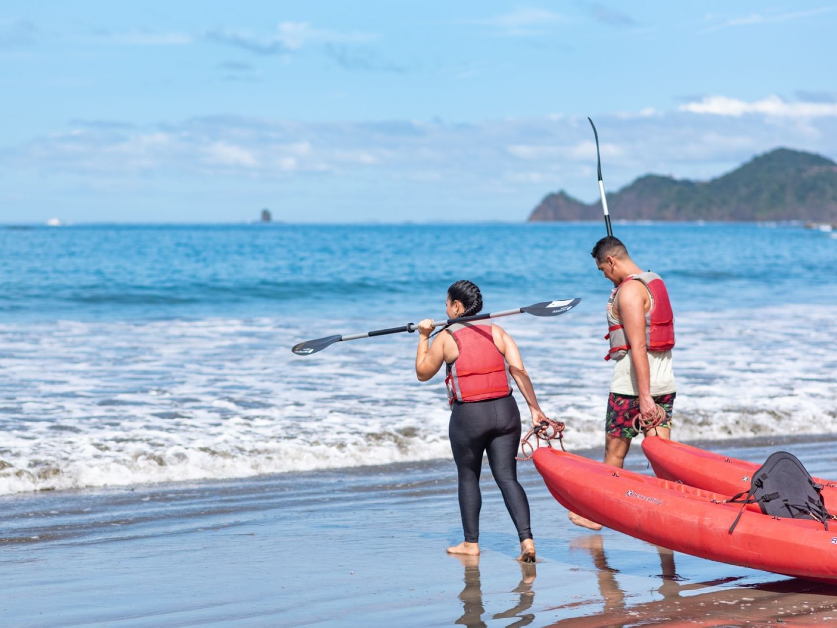 Couple holding kayaks at the Beach near Villas Sol Beach Resort