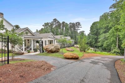 White cottages along a winding path, surrounded by greenery and boulders under a clear sky, by Cottages at Laurel Brooke
