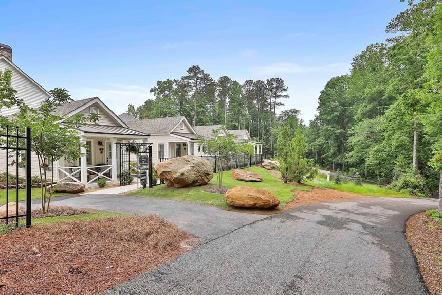 White cottages along a winding path, surrounded by greenery and boulders under a clear sky, by Cottages at Laurel Brooke