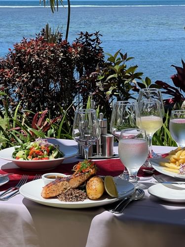 Plates of food and drinks on a table with ocean view at Pappagallo in Warwick Fiji Resort and Spa Korolevu