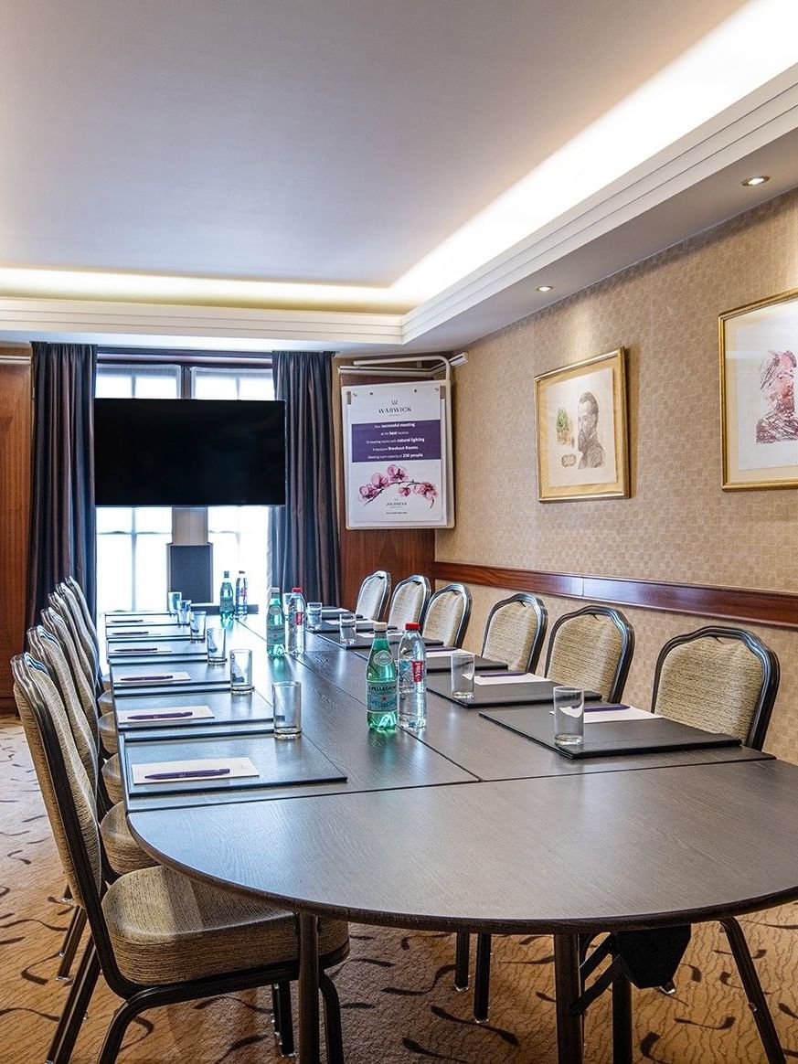 Ensor room setup with chairs and table facing hanging TV at Warwick Grand-Place Brussels