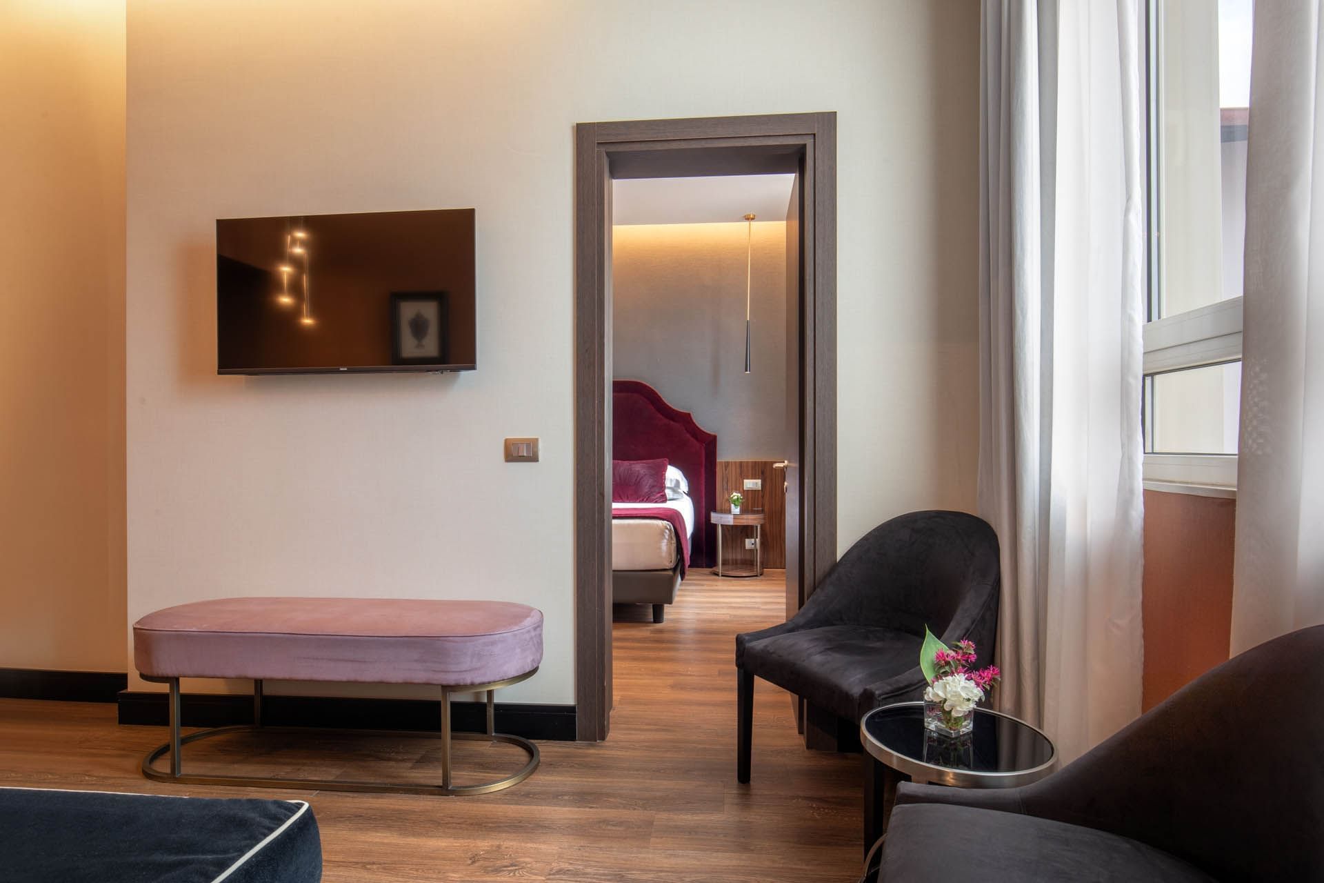 Modern Guardian Suite at The Guardian Hotel with a TV, purple bench, stylish seating, and a cozy bedroom in view