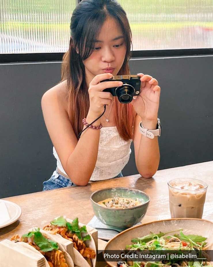 Lady photographing dishes served in a Restaurant table near Imperial Lexis, best Malaysian Restaurants Kuala Lumpur