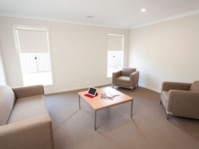 Living room with couch, chairs, and coffee table at La Trobe University Regional Housing – Shepparton.
