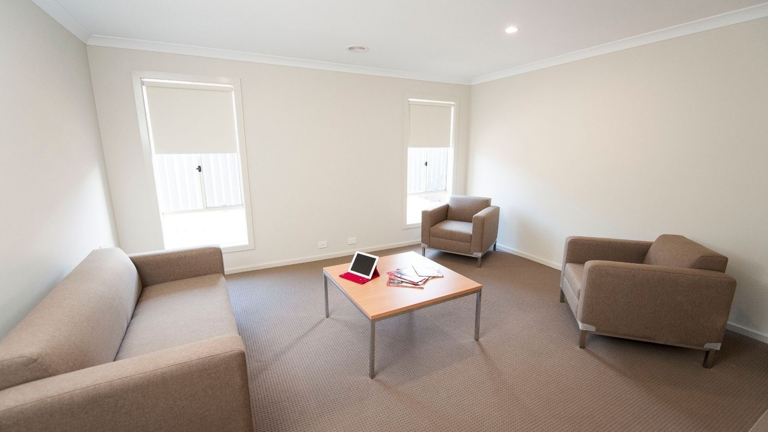 Living room with couch, chairs, and coffee table at La Trobe University Regional Housing – Shepparton.