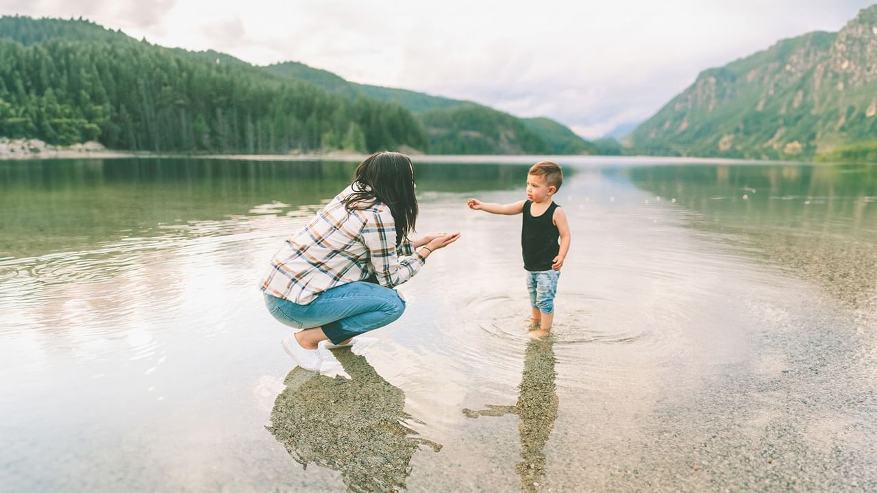 Mother and son playing in a lake next to the mountains