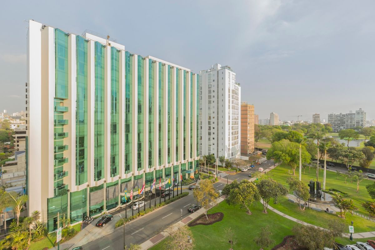 Exterior view of Hotel Los Delfines & Casino with motor lobby, surrounded by greenery and cityscape