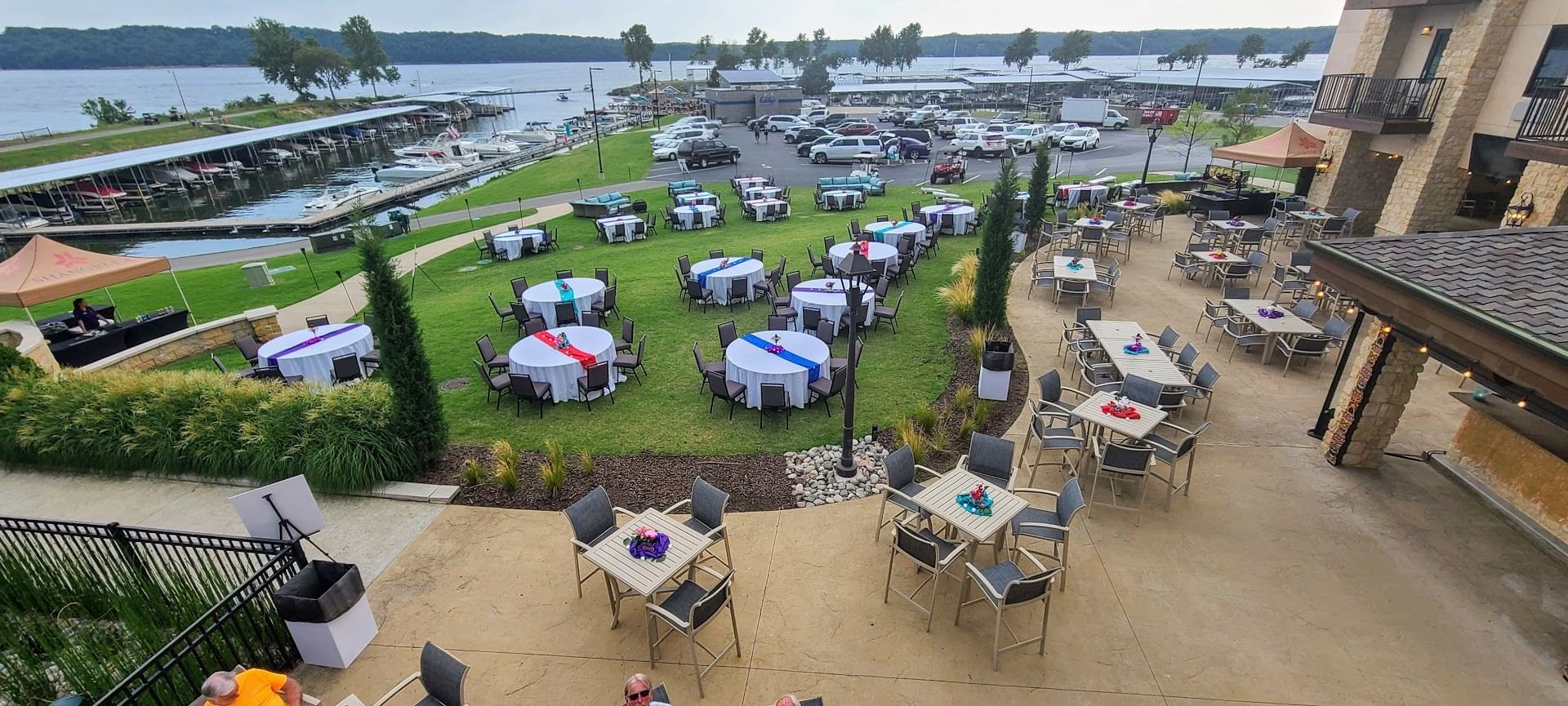 Outdoor event space with dining tables on lawn and patio, overlooking a marina at Shangri-La Monkey Island