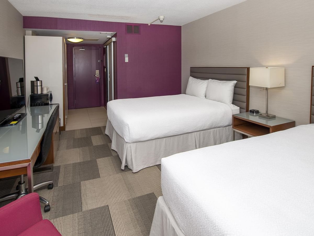 Modern guest room with two queen beds, work desk, and purple accent wall at Coast Prince George Hotel in Prince George.