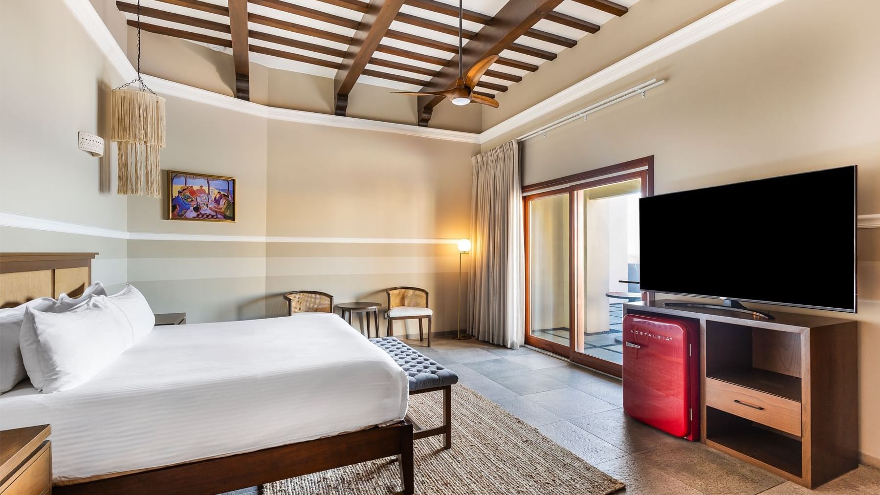 TV facing bed and balcony with seating in a room at Curamoria Collection