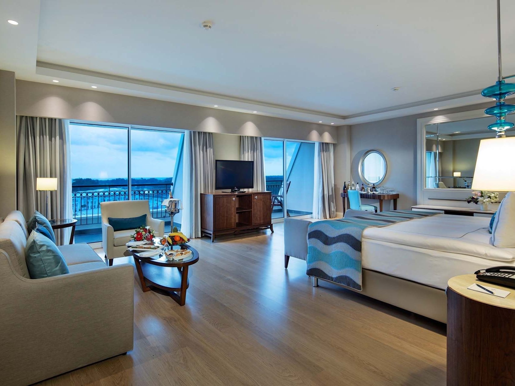 Sitting area & TV by the bed in Deluxe Room with wooden floors at Titanic Deluxe Golf Belek