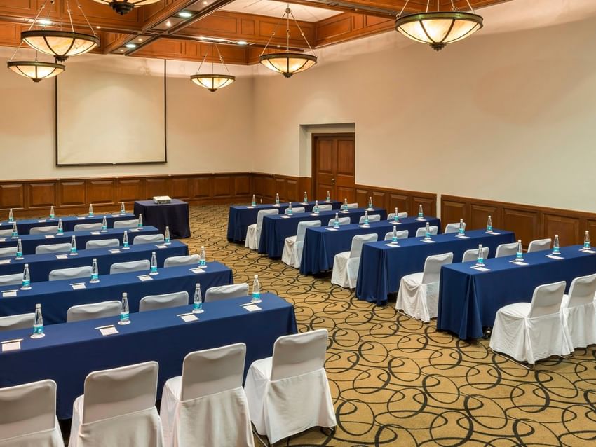 Cantera meeting room setup with blue-clothed tables and white chair covers at Camino Real Puebla Angelopolis