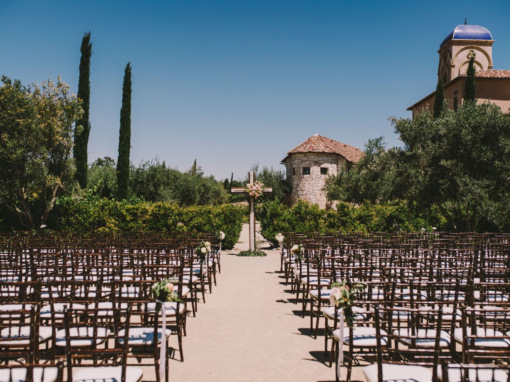 Looking down the aisle of rows of chairs set for an outdoor wedding